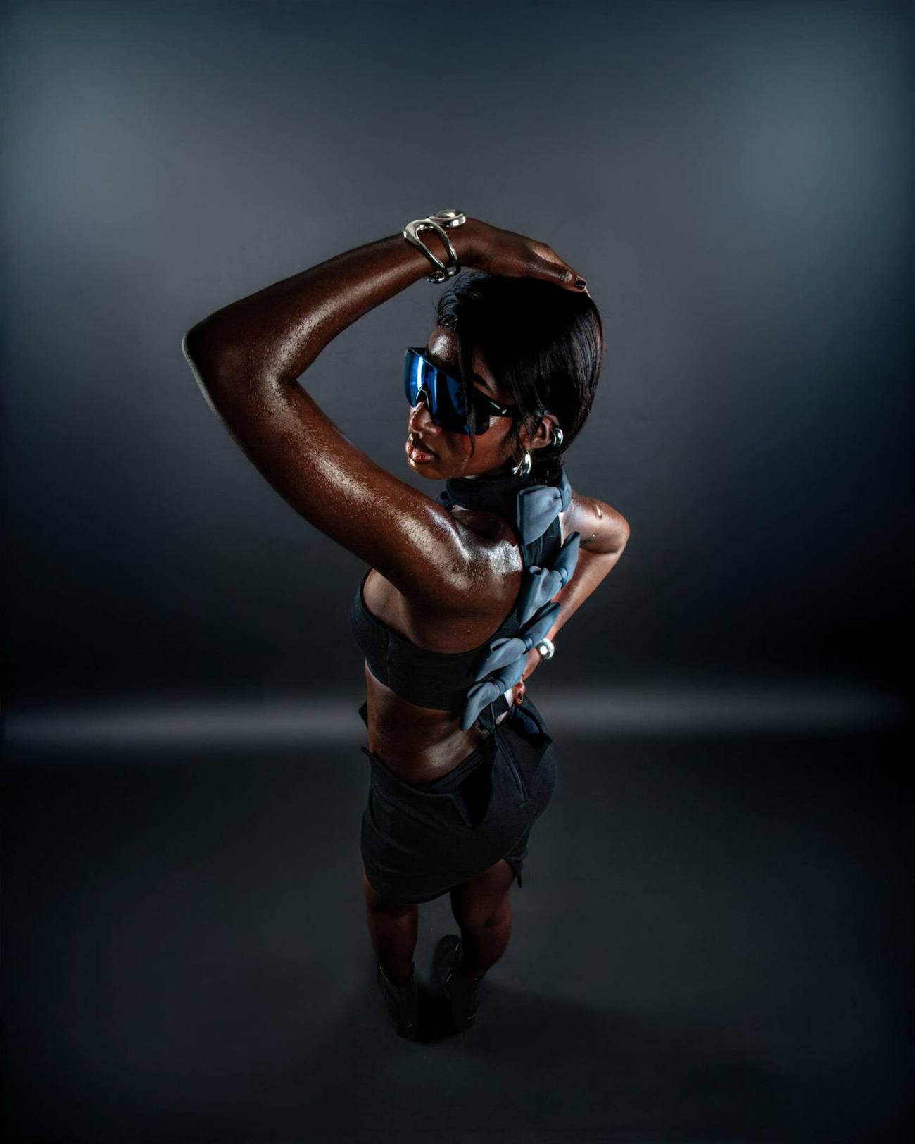 Mannequin de dos portant un top noir à nœuds, lunettes bleutées, shooting studio pour TGC