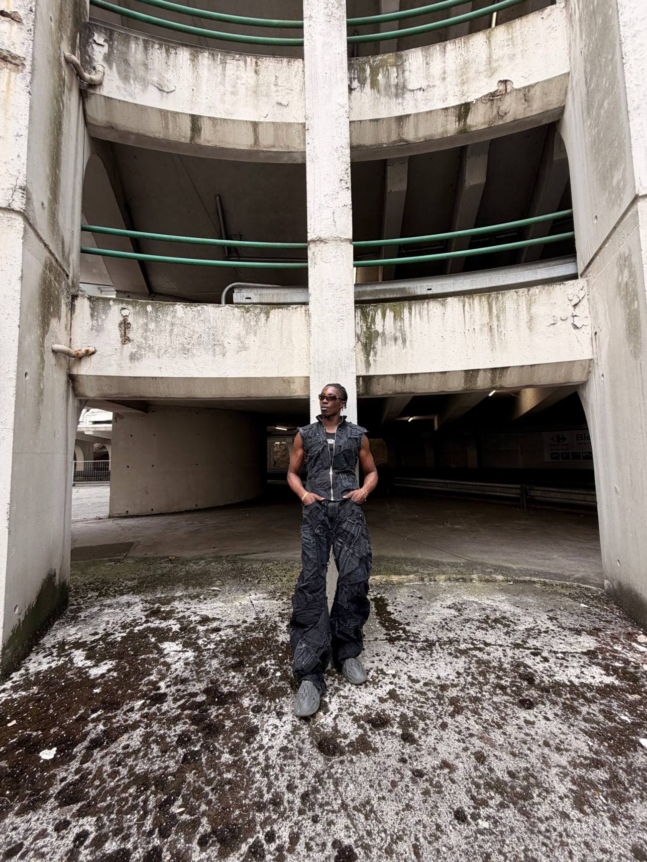 Homme en gilet et jean patchwork debout dans un parking en spirale, collection PATCHWORK de Scavengers