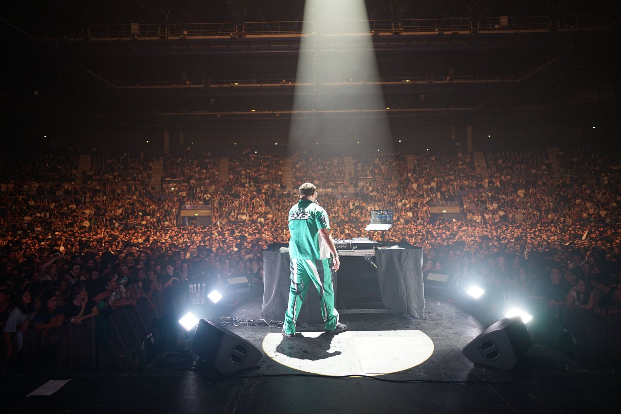 DJ Zayon sur scène face à la foule du Zénith, sous un faisceau de lumière